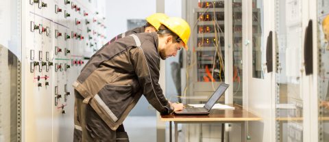 Technicien analysant un schéma électrique pour diagnostic industriel.